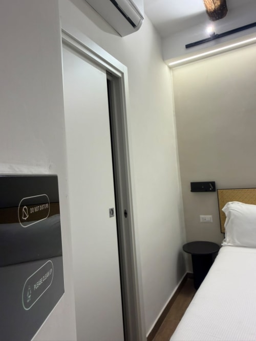 Camera d'hotel moderna al Salotto Toledo di Napoli con pareti bianche, porta scorrevole e letto con biancheria bianca