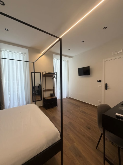 Elegante camera king deluxe moderna al Salotto Toledo, lussuoso B&B a Napoli, con letto a baldacchino nero contemporaneo e TV a schermo piatto