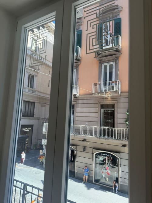 Vista dal balcone di Napoli su palazzo rosa con negozi e strada, suite di lusso Salotto Toledo