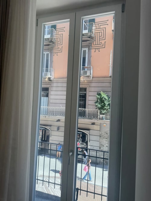 Vista dal balcone della camera di lusso Salotto Toledo a Napoli che si affaccia sulla strada storica e la facciata color pesca