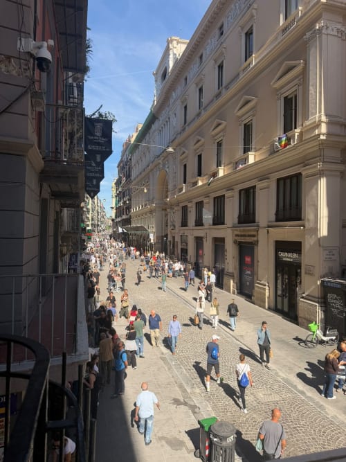 Vivace strada pedonale a Napoli con eleganti edifici storici, vista dal balcone della suite Salotto Toledo