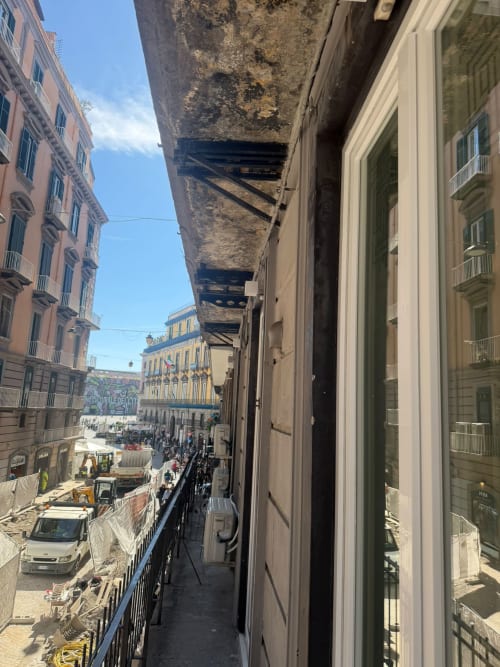 Vista di una stretta strada napoletana dal balcone di Salotto Toledo con edifici storici e la città sottostante