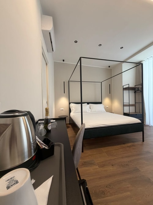 Letto a baldacchino moderno con cornice nera in camera di lusso a Napoli, bollitore e minibar visibili