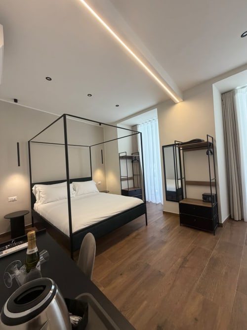 Moderna camera di lusso al Salotto Toledo Napoli con letto a baldacchino nero, pavimenti in legno, illuminazione d'atmosfera e vista sulla città