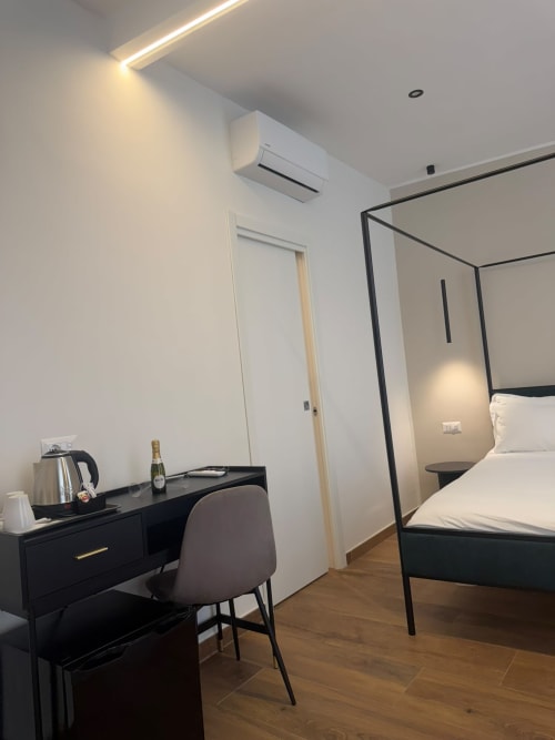Camera da letto di lusso moderna al Salotto Toledo Napoli con letto a baldacchino nero, scrivania, aria condizionata e elegante bianco