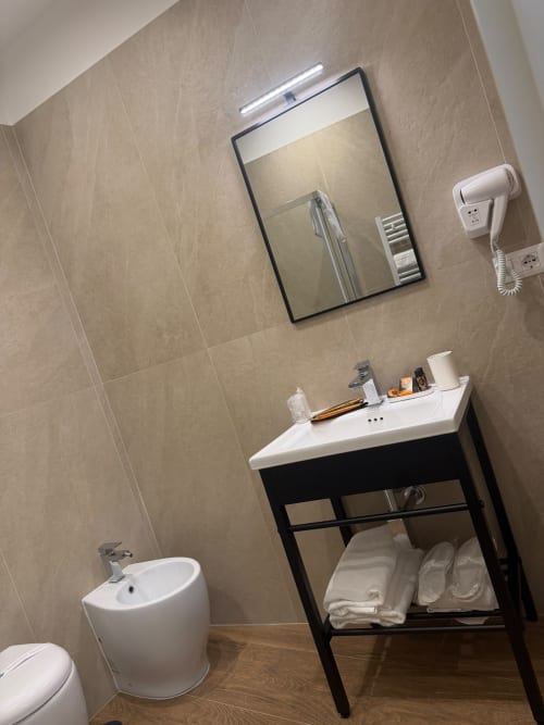 Bagno moderno nella suite Salotto Toledo con vanity nero, lavabo bianco, water e specchio con illuminazione a Napoli