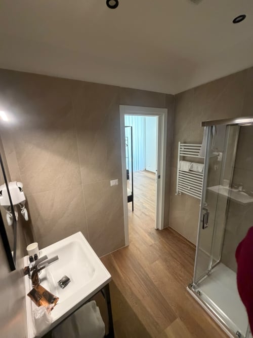 Bagno moderno del lussuoso B&B Salotto Toledo a Napoli con doccia, lavabo, scaldarancia e rivestimento effetto legno