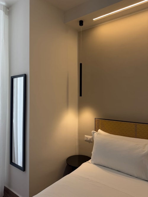 Camera moderna del lussuoso hotel Salotto Toledo a Napoli con pareti beige, biancheria bianca, illuminazione a sospensione e design minimalista