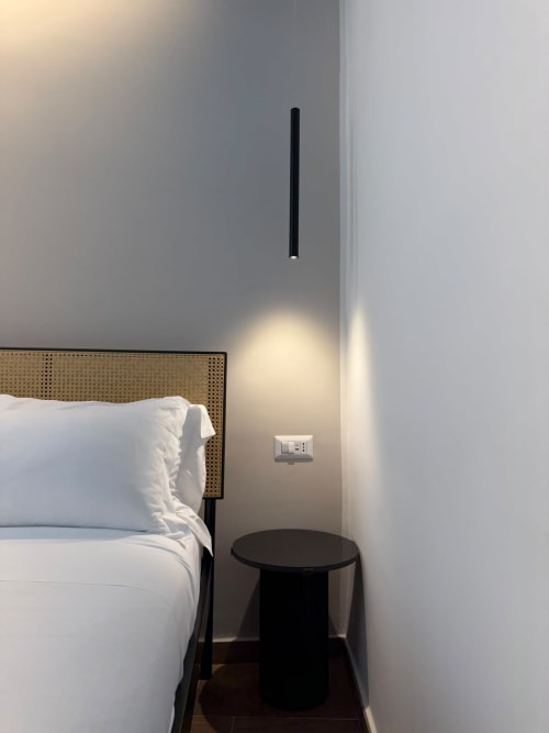 Angolo camera moderna nel lussuoso B&B Salotto Toledo a Napoli, con testata in rattan, biancheria bianca, lampada a sospensione nera
