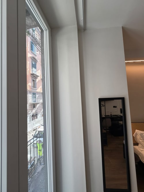 Corridoio moderno dell'hotel Salotto Toledo a Napoli con vista sulla città e finestre che si affacciano su edifici storici