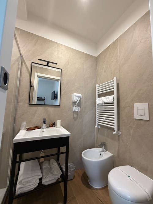 Bagno moderno nella suite Salotto Toledo dell'hotel di lusso a Napoli con vanity, bidet, scaldasalviette e piastrelle beige