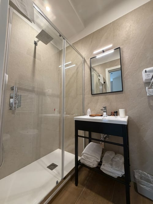 Bagno di lusso moderno al Salotto Toledo Napoli con doccia a filo pavimento, vanity nera e scaldasalviette elettrico