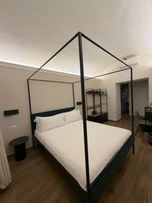 Letto a baldacchino nero moderno con biancheria bianca nella suite di lusso dell'hotel Salotto Toledo Napoli