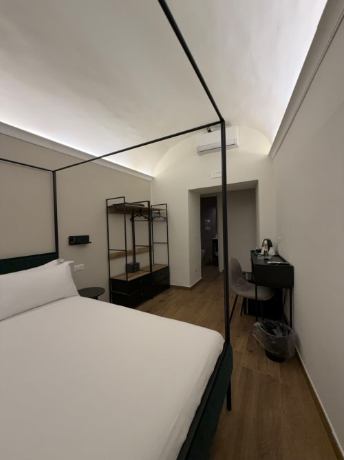 Camera moderna presso Salotto Toledo, lussuoso BnB a Napoli, con letto a baldacchino in metallo nero e pavimentazione in legno