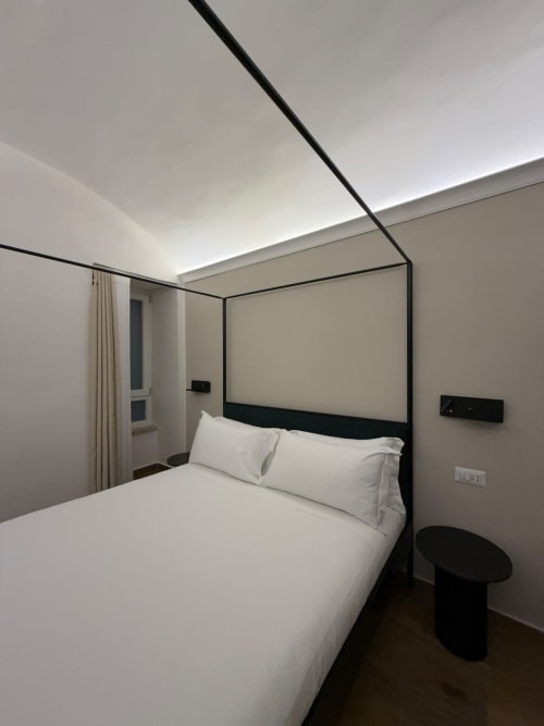 Camera moderna nel lussuoso B&B Salotto Toledo a Napoli con letto a baldacchino nero, biancheria bianca e design minimalista