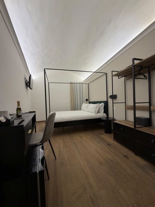 Camera da letto di lusso moderno a Salotto Toledo Napoli con letto a baldacchino, scrivania e arredamento nero contemporaneo
