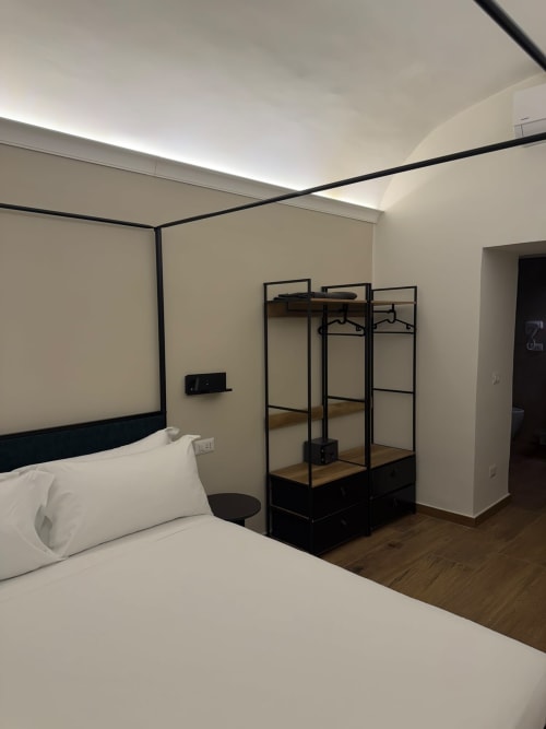 Camera moderna nel lussuoso B&B Salotto Toledo a Napoli con letto a baldacchino, armadio in metallo nero e design contemporaneo