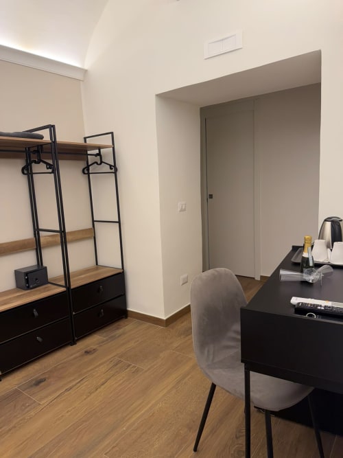 Camera moderna presso Salotto Toledo Napoli con scrivania, scaffali neri, pavimenti in legno e arredamento contemporaneo