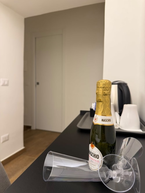 Bottiglia di Prosecco Maschio con flûte di champagne su scrivania scura nella suite Salotto Toledo di Napoli