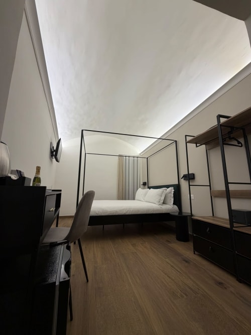 Camera d'hotel di lusso moderno a Salotto Toledo Naples con letto a baldacchino, pavimenti in legno e arredamento minimalista bianco e nero