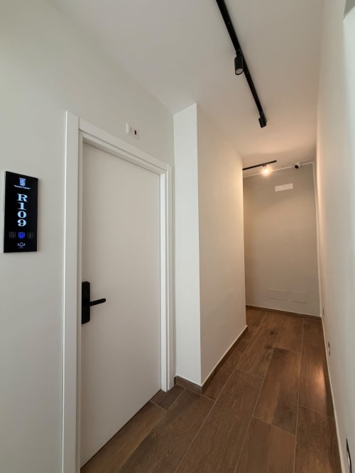 Corridoio moderno dell'hotel di lusso Salotto Toledo a Napoli, con porte bianche e pavimentazione in legno che conducono alle camere