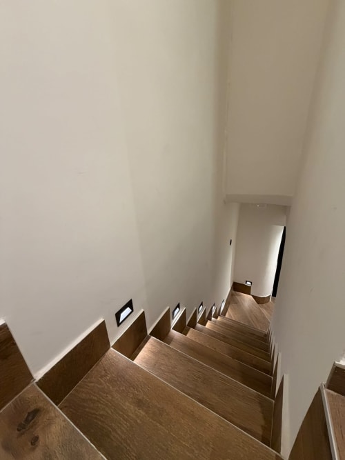 Scala in legno con pareti bianche nella lussuosa B&B Salotto Toledo a Napoli, che conduce al corridoio dell'hotel con finiture moderne