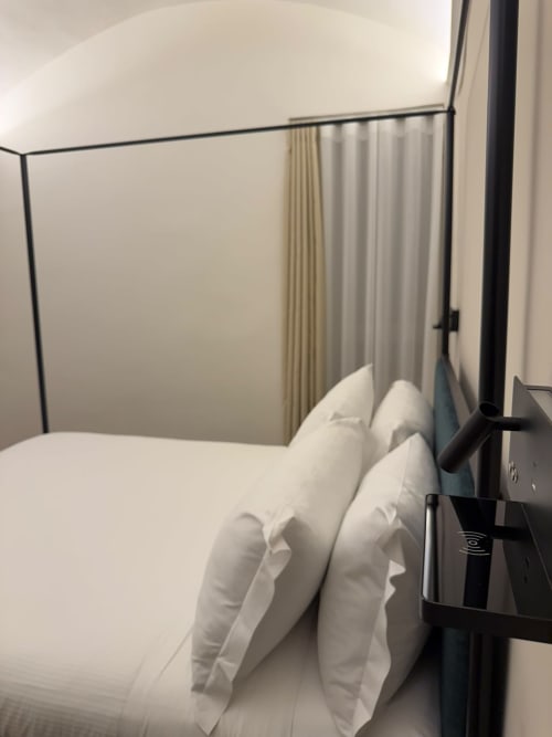 Camera moderna nel lussuoso hotel Salotto Toledo di Napoli con elegante letto a baldacchino e tende con vista sulla città