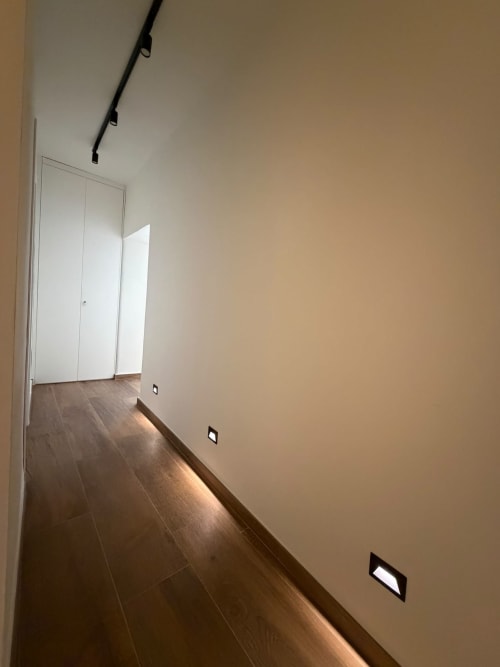 Corridoio moderno nella suite di lusso Salotto Toledo con pavimento in legno scuro, pareti bianche, illuminazione a binario e design contemporaneo