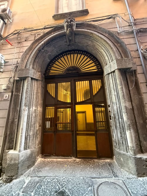 Splendido portale con arco ornato e sovraluce giallo a ventaglio al Salotto Toledo, lussuoso B&B a Napoli