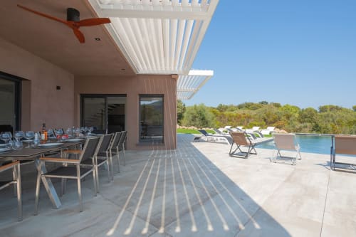 Terrasse de la Villa Poggioli avec coin repas, transats, piscine privée et vue sur la mer à Zonza
