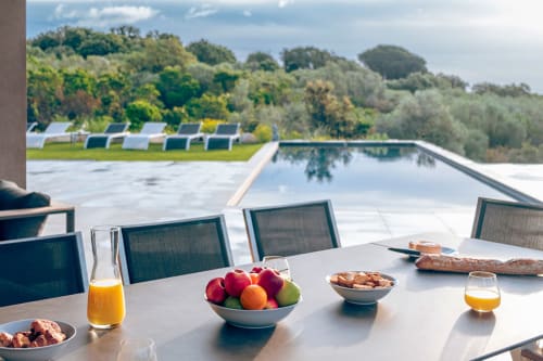 Terrasse de la Villa Poggioli avec petit-déjeuner face à la piscine privée et la campagne corse aux Villas d'A Storia