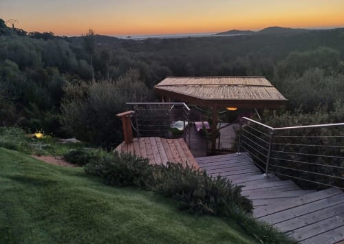 Terrasse de la Villa Poggioli au coucher de soleil avec deck en bois, pergola et oliviers dominant la vallée corse, Les Villas d'A