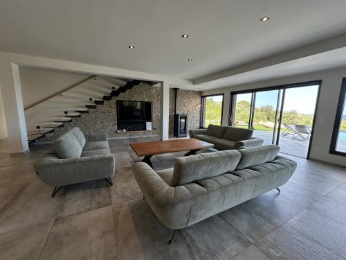 Salon moderne avec canapés gris, table en bois et cheminée en pierre à la Villa Poggioli à Zonza