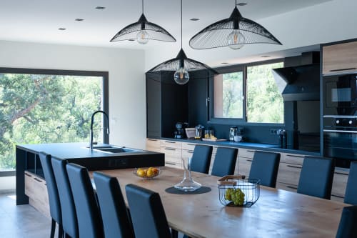 Cuisine et salle à manger modernes à la Villa Poggioli des Villas d'A Storia, Zonza, avec suspensions noires et vue mer.