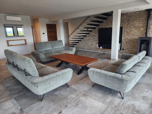 Séjour moderne à la Villa Poggioli à Zonza avec fauteuils gris, table en bois, escalier flottant et foyer en pierre