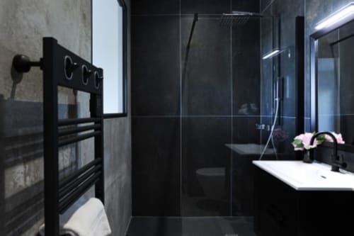 Salle de bains moderne noire à la Villa Poggioli avec douche à l'italienne, sèche-serviettes chauffant, meuble vasque blanc et composition florale aux Les