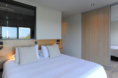 Chambre moderne de la Villa Poggioli aux Villas d'A Storia en Corse, avec vue mer, tête de lit en bois clair et