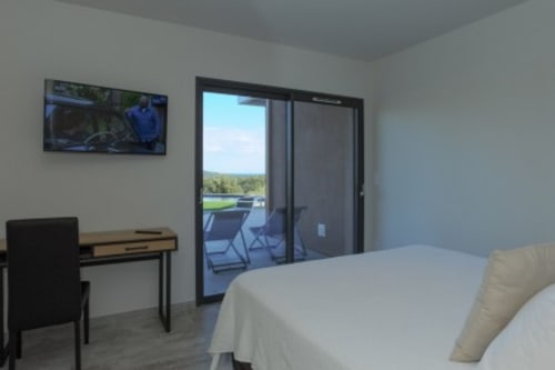 Chambre moderne aux Villas d'A Storia avec vue mer, bureau, TV et accès à terrasse privée surplombant le paysage corse