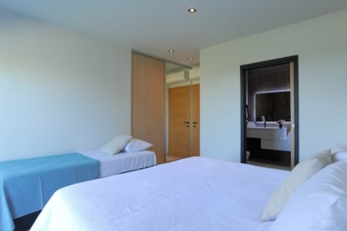 Chambre moderne de la Villa Poggioli à Zonza avec lits jumeaux, armoire et salle de bains attenante avec vanité