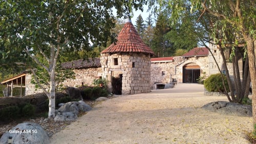 Furanelle BnB, bâtisse en pierre avec tourelle aux tuiles rouges à Saint Etienne, entourée d'arbres et cour en gravier