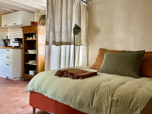 Chambre douillette du gîte Les Maraîchades en Sologne, avec literie crème, mobilier en bois et rideaux donnant sur le jardin.
