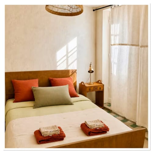 Chambre lumineuse du gîte Les Maraîchades en Sologne avec tête de lit beige, oreillers orange et serviettes pliées sur le lit