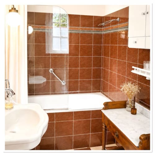 Salle de bains luxueuse aux murs en carrelage terracotta, douche à l'italienne, baignoire et plan de travail en marbre au gîte Les Maraîchades
