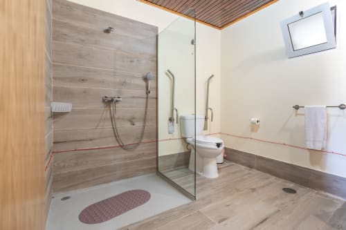 Modern wheelchair accessible bathroom at Garry's Holiday Rentals villa in Prazeres with walk-in shower, toilet, and