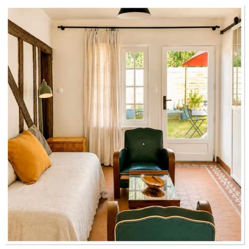 Chambre de charme aux Maraîchades avec vue sur le jardin, lit à baldaquin, fauteuil vert et portes-fenêtres