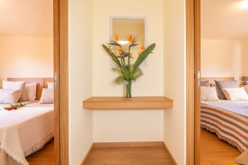 Hallway at Garry's Holiday Rentals villa in Prazeres with bird of paradise flowers on wooden shelf between bedrooms