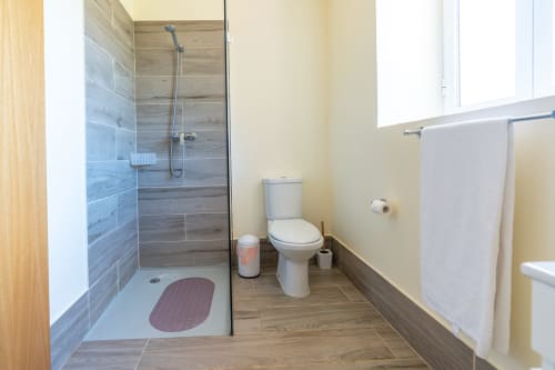 Modern bathroom at Garry's Holiday Rentals villa with walk-in shower, toilet, and towel rack