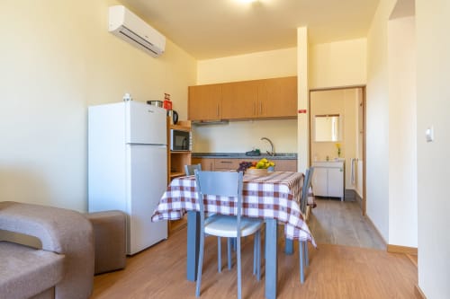 Open-plan kitchen-dining area in Quinta frizado villa, Prazeres, with wooden cabinets, dining table, and white refrigerator