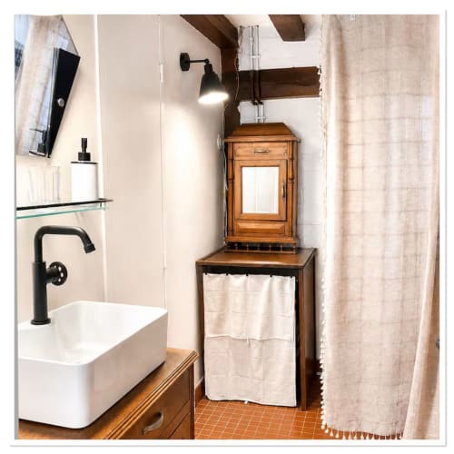 Salle de bain charmante aux Maraîchades avec lavabo blanc, robinetterie noire, meuble en bois et décor rustique en Sologne