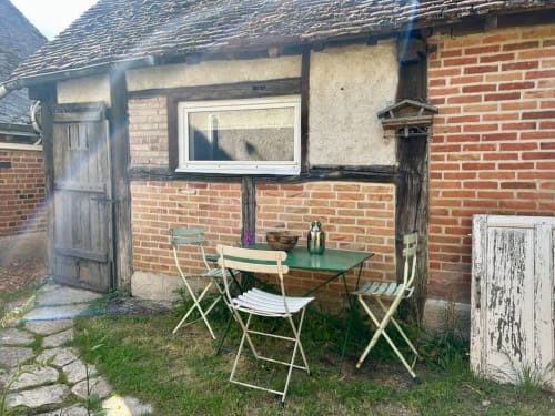 Terrasse de jardin accueillante au gîte Les Maraîchades avec table, chaises et bâtiment en brique en Sologne